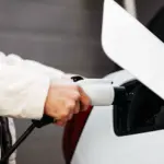 Ein Mann steckt den Stecker der Wallbox in den Anschluss am Auto