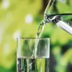 Wasser wird aus einer gläsernen Karaffe in ein Glas gefüllt